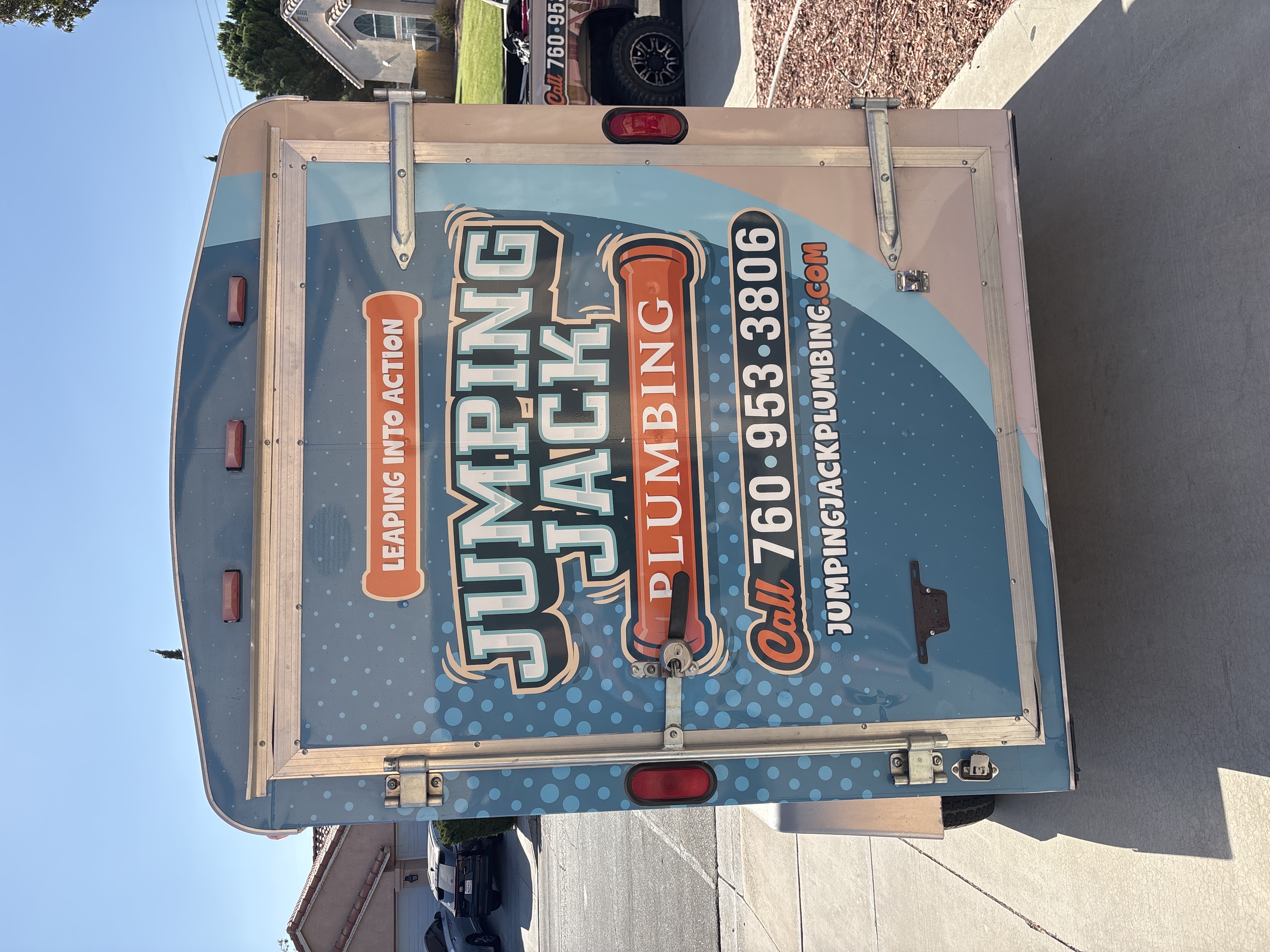 Jumping Jack Plumbing branded trailer with phone number and leaping into action slogan