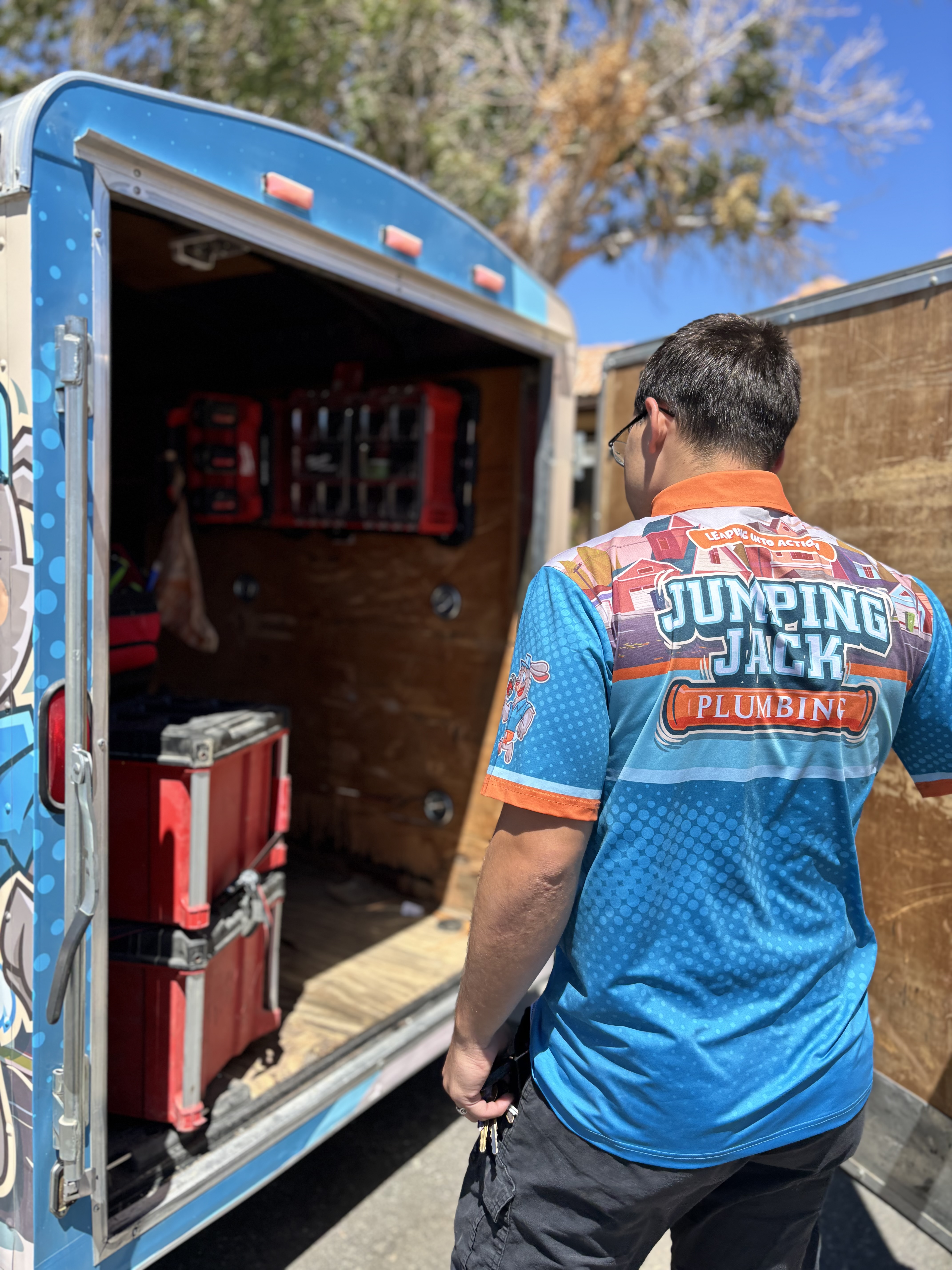 Jumping Jack Plumbing technician loading drain service tools from the trailer